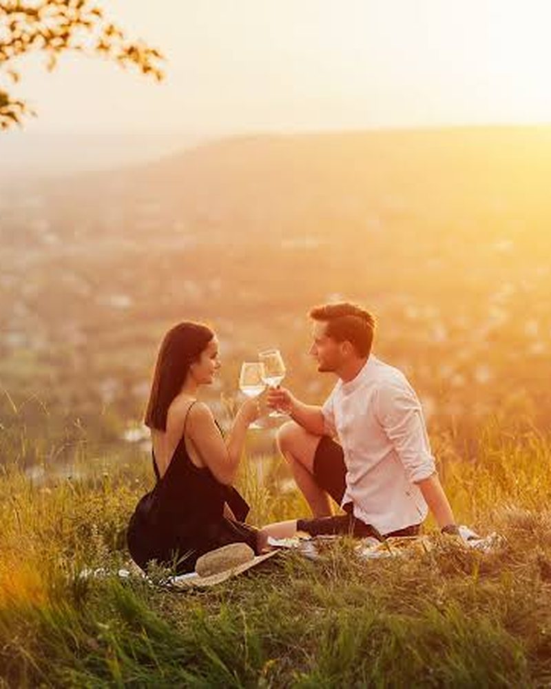 Casal brindando com vinho ao pôr do sol na Toscana