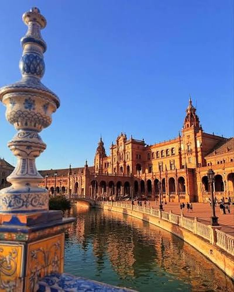 Praça de Espanha em Sevilha, com azulejos e reflexo no canal ao entardecer