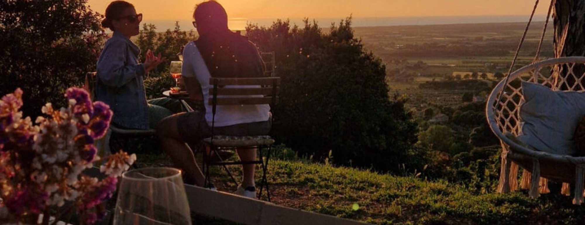 Casal jantando ao entardecer em terraço com vista para o campo italiano