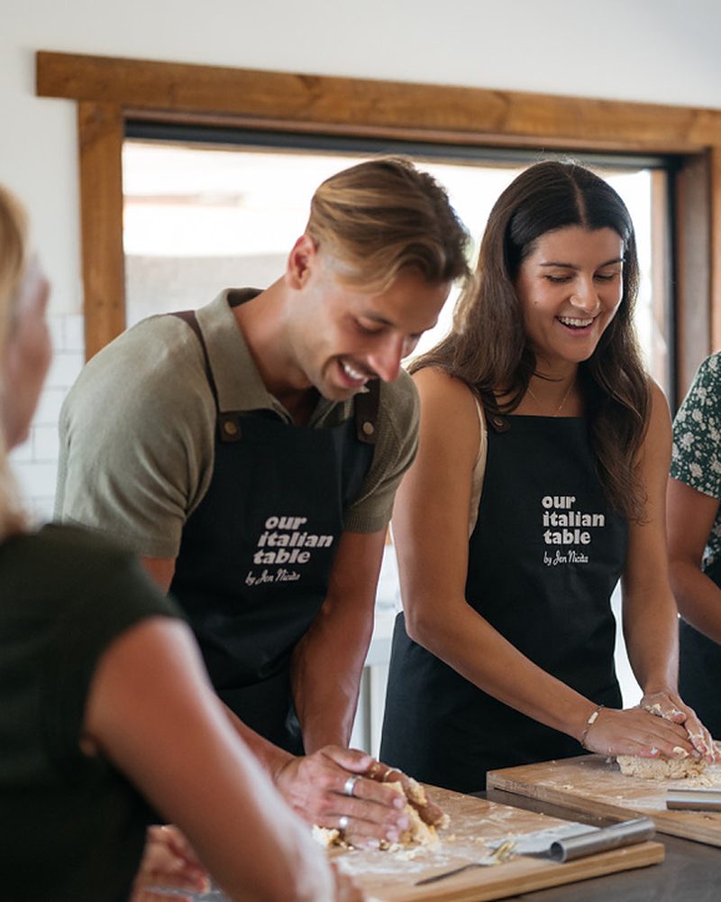 Grupo em aula de culinária italiana preparando massa fresca à mão