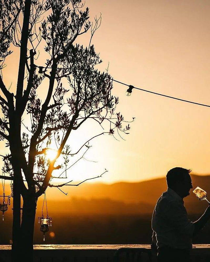 Casal jantando ao entardecer com vista para os vinhedos da Toscana