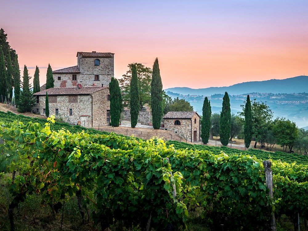 Vila de pedra na Toscana entre ciprestes e vinhedos ao entardecer