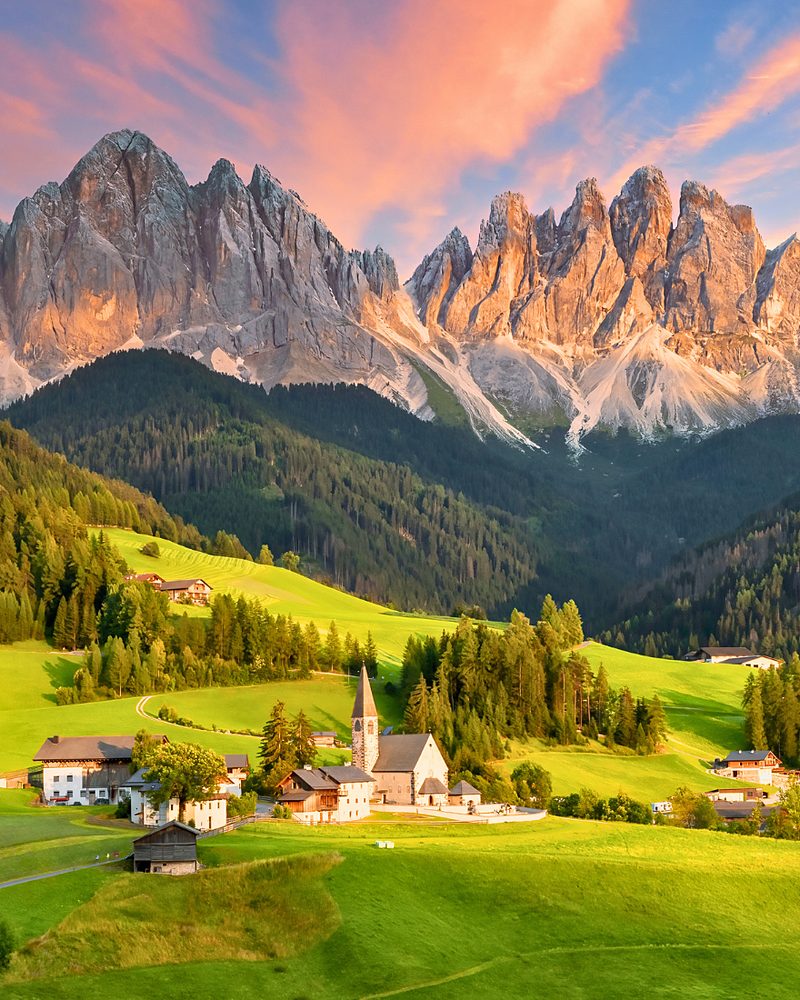 Igreja de montanha diante dos picos dos Dolomitas ao entardecer