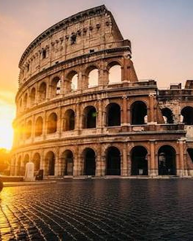 Coliseu de Roma ao amanhecer, com ruas de paralelepípedo